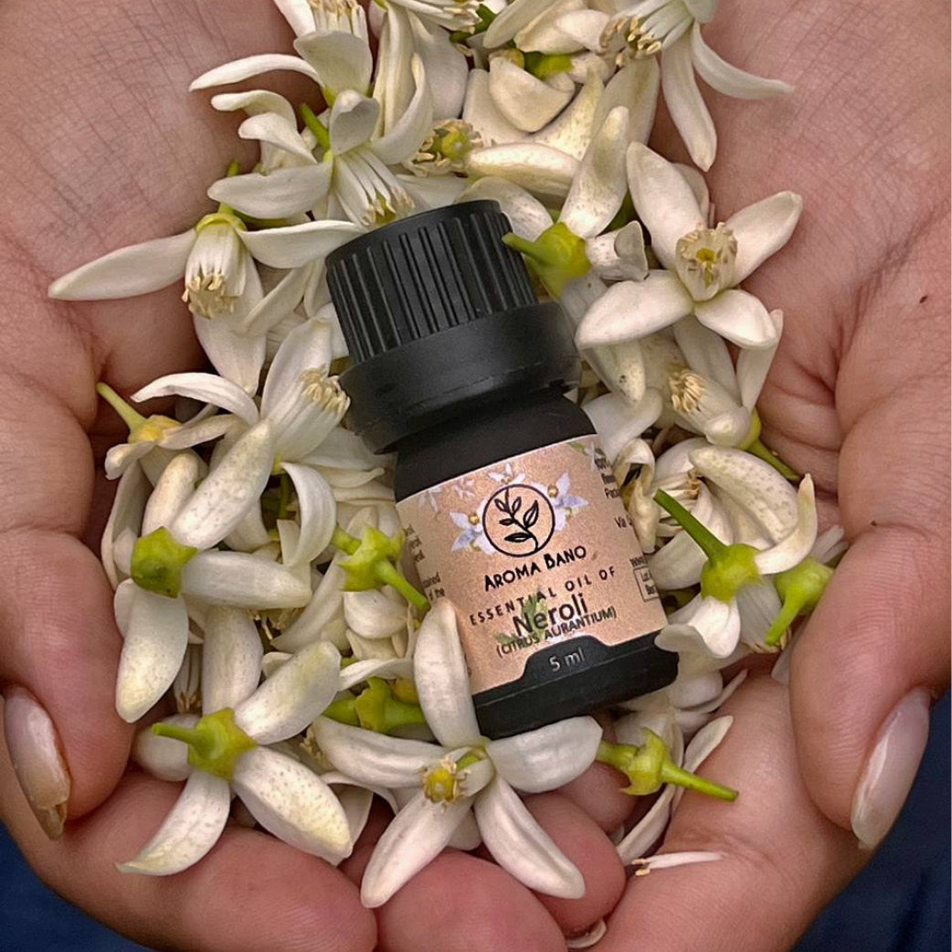 Olio essenziale di Neroli Aroma Bano in bottiglia da 5 ml appoggiata su fiori freschi di arancio amaro
